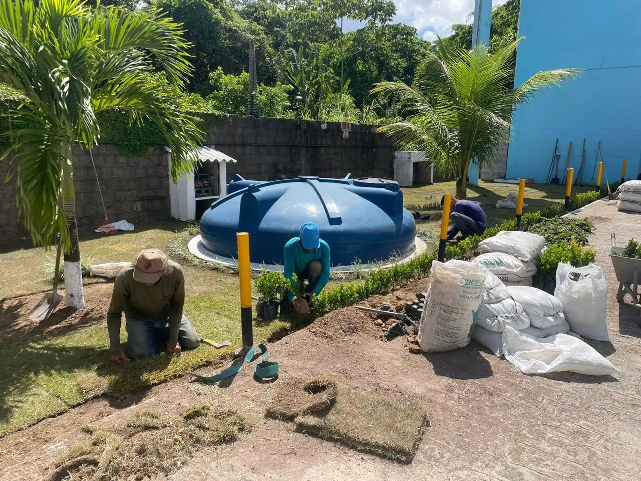 Equipe da Quati assentando placas de grama em rolo em jardim de residência